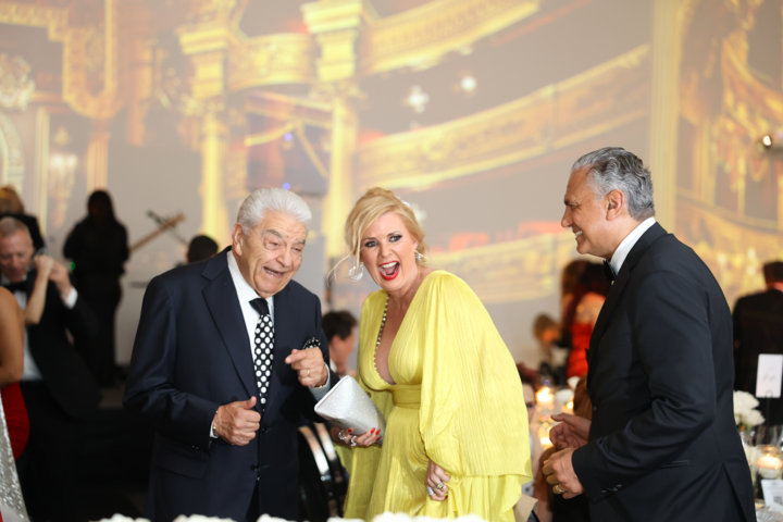 Don Francisco, Sissi Fleitas, and Moataz Rafaie share a laugh at a formal gala with a grand opera backdrop.